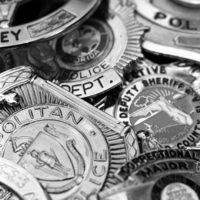 Black and white image of a pile of police badges